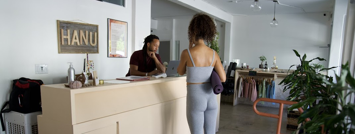 The HANU front desk — a member checking in with a mat